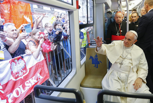 Pope Francis waives to a cheering crowd of faithful as he drives by in a public transportation tram he used to reach the venue of the World Youth Days in Krakow, Poland, Thursday, July 28, 2016. Pope Francis is in Poland for a five-day pastoral visit and to attend the 31st World Youth Days. (Photo by Stefano Rellandini/Pool photo via AP Photo)