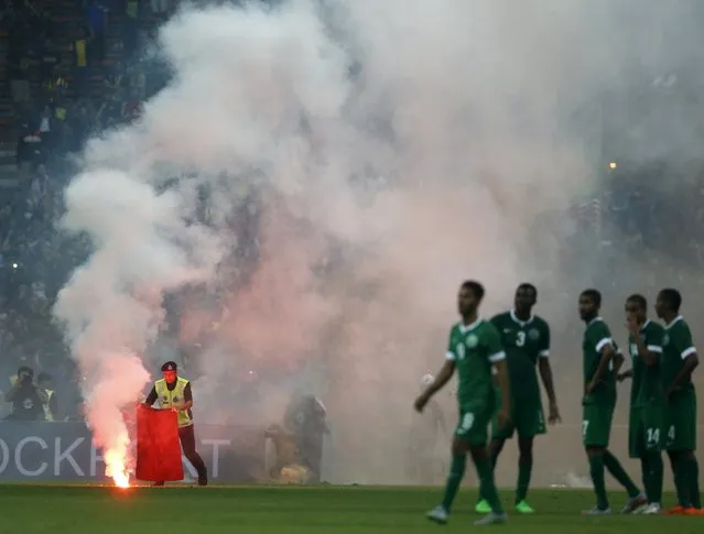 A police officer extinguishes a flare on the pitch during the 2018 World Cup qualifying soccer match between Malaysia and Saudi Arabia in Kuala Lumpur, Malaysia, September 8, 2015. The match was disrupted by flares and fights in the stands minutes before the final whistle was blown, according to local media. (Photo by Olivia Harris/Reuters)