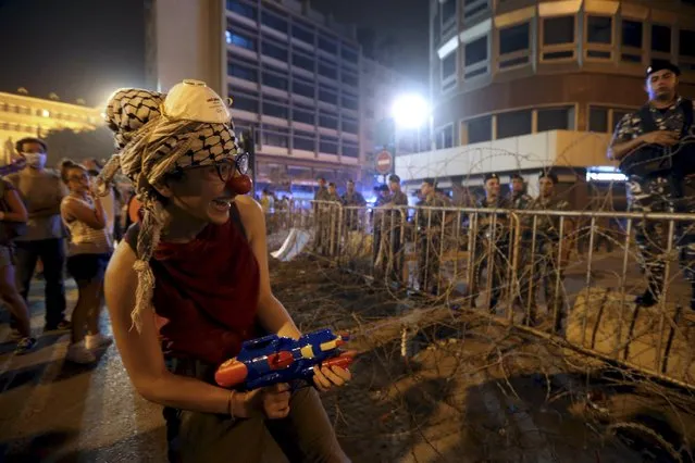 A protester wearing a red nose sprays Lebanese security members with a water gun during a protest against perceived government failures, including a rubbish disposal crisis, near the government palace in downtown Beirut, Lebanon September 9, 2015. (Photo by Hasan Shaaban/Reuters)