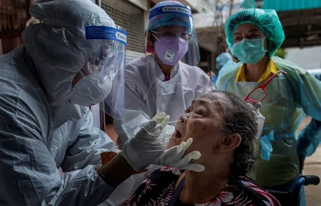 Health workers collect a nasal swab sample from a woman to test for the coronavirus in Bangkok, Thailand, Wednesday, May 6, 2020. Thai health workers started testing community of about 1600 people of Klong Toey slum at a nearby Buddhist temple. (Photo by Gemunu Amarasinghe/AP Photo)