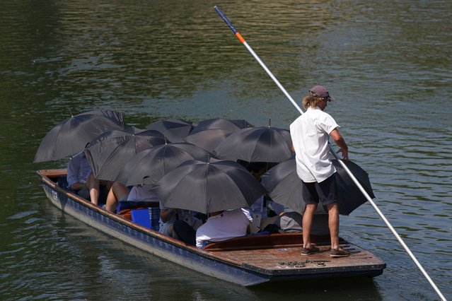 People under umbrellas being punted along the River Cam in Cambridge, one of the hottest places in the UK on Tuesday, July 19, 2022. Temperatures have reached 40C for the first time on record in the UK, with 40.2C provisionally recorded at London Heathrow, the Met Office has said. (Photo by Jacob King/PA Images via Getty Images)