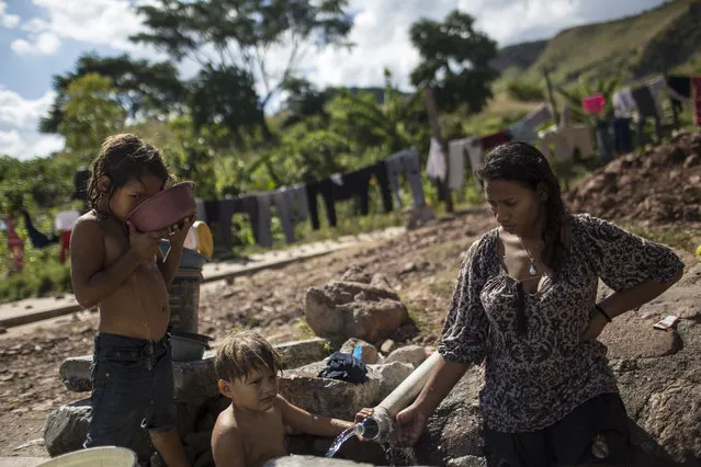 Zamaria Canale, 6, drinks water next to her brother Henry, 3, while helping her mother Belkin wash the clothes on a pipe outside, due to the lack of water in their house in Tegucigalpa, Honduras, Tuesday, November21, 2017. Honduras will hold general elections on Sunday, Nov. 26. (Photo by Rodrigo Abd/AP Photo)