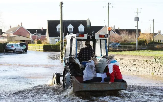 Women take a lift from a tractor up Manor street in Mountmellick, Co Laois, Ireland on November 23, 2017, after three rivers burst their banks and flooded dozens of homes. (Photo by Brian Lawless/PA Images via Getty Images)