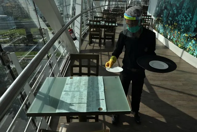 A waiter wearing a protective face mask and a shield sets a table inside the Biswa Bangla Gate restaurant, after authorities eased lockdown restrictions that were imposed to slow the spread of the coronavirus disease (COVID-19), in Kolkata, India, June 25, 2020. (Photo by Rupak De Chowdhuri/Reuters)