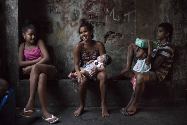 In this September 9, 2017 photo, residents sit in a corridor inside a squatter building that used to house the Brazilian Institute of Geography and Statistics (IBGE) in the Mangueira slum of Rio de Janeiro, Brazil. Despite the hardscrabble existence, there is a strong sense of community among the hundreds of people occupying the building. (Photo by Felipe Dana/AP Photo)