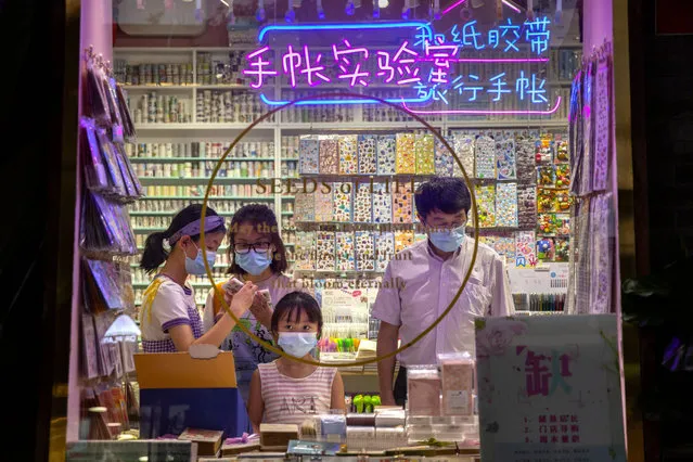 People wearing face masks to protect themselves against the coronavirus shop in a store along a pedestrian shopping street in Beijing, Wednesday, July 22, 2020. Numbers of cases in China's latest virus outbreak continued to fall Wednesday, with several new cases in the northwestern region of Xinjiang. (Photo by Mark Schiefelbein/AP Photo)