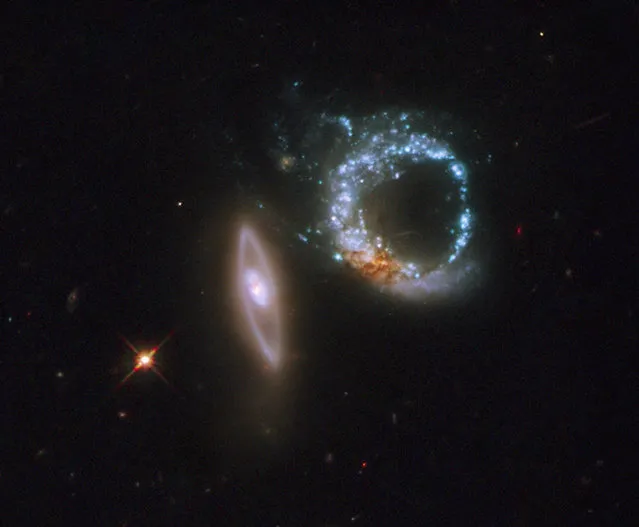 A pair of gravitationally interacting galaxies called Arp 147. The left-most galaxy is relatively undisturbed apart from a smooth ring of starlight. It appears nearly on edge to our line of sight. The right-most galaxy, resembling a “zero”, exhibits a clumpy, blue ring of intense star formation. (Photo by Reuters/NASA)