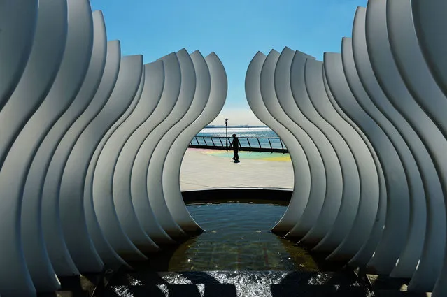 A man walks by a sculpture at the seafront promenade on July 27, 2020 in Qingdao, Shandong Province of China. (Photo by Wang Haibin/VCG via Getty Images)