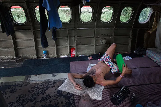 A Thai man fans himself with a piece of plastic while listening to a battery-powered radio in his home in a disused airplane on September 12, 2015 in Bangkok, Thailand. (Photo by Taylor Weidman/Getty Images)