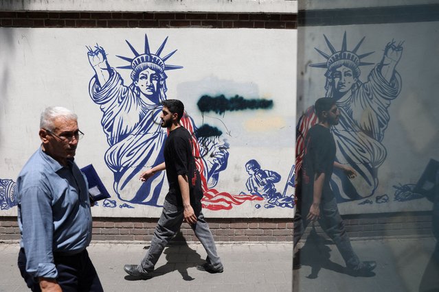 People walk past an anti-U.S. mural on a street in Tehran, Iran on May 11, 2025. (Photo by Majid Asgaripour/WANA via Reuters)