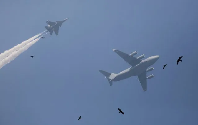 Birds fly past as Indian Air Force Sukhoi fighter jet, left, and Indian Air Force C-17 Globemaster display a fly-by during the rehearsals ahead of annual Republic Day parade in New Delhi, India, Thursday, January 18, 2018. India celebrates Republic Day on January 26. (Photo by Altaf Qadri/AP Photo)