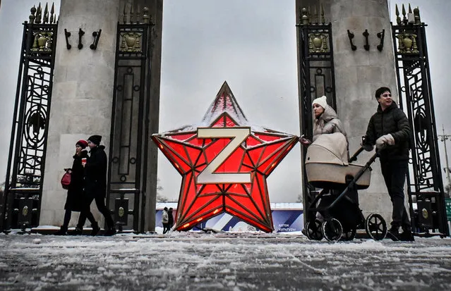 People walk past a New Year decoration Kremlin Star, bearing a Z letter, a tactical insignia of Russian troops in Ukraine, at the Gorky Park in Moscow on December 29, 2022. (Photo by Alexander Nemenov/AFP Photo)