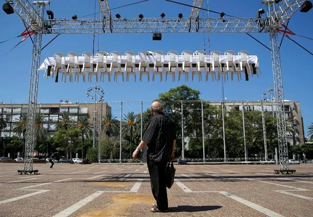 A man looks at a festive table, similar to those which will be set by Jews when they celebrate the upcoming Jewish New Year, as it is lifted above the ground as part of an installation entitled “the unreachable meal” organised by Latet, a charity established to help fight poverty in Israel, and installed by creative group “no,no,no,no,no, yes” at Rabin Square in Tel Aviv, Israel September 18, 2016. (Photo by Amir Cohen/Reuters)