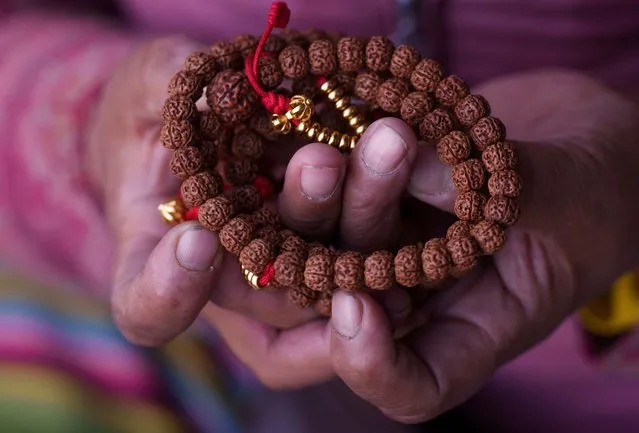 A Buddhist woman offers prayers with beads on her hand during Monlam prayers at Sherpa monastery in Kathmandu, Nepal, Monday, January 2, 2023. Monlam is an annual event where Buddhist monks pray for world peace. (Photo by Niranjan Shrestha/AP Photo)