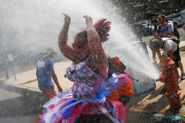 A supporter of U.S. Senator Bernie Sanders cools off from a water hydrant as she takes part in a protest march ahead of the 2016 Democratic National Convention in Philadelphia, Pennsylvania on July 24, 2016. (Photo by Adrees Latif/Reuters)