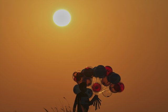 A boy sells balloons as the sun sets over the Mediterranean Sea in Beirut, Tuesday, June 17, 2025. (Photo by Bilal Hussein/AP Photo)