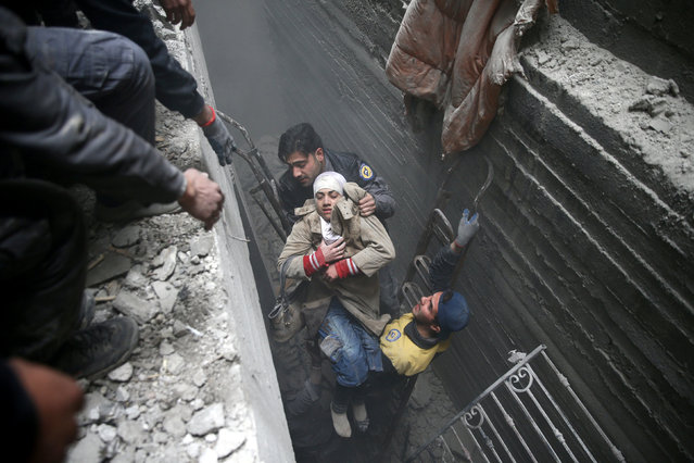 Syria Civil Defence members help an unconscious woman from a shelter in the besieged town of Douma, Eastern Ghouta, Damascus, Syria February 22, 2018. (Photo by Bassam Khabieh/Reuters)