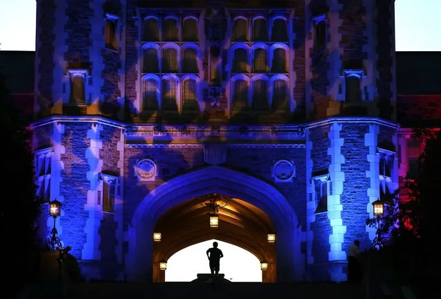 A man jogs up stairs to Brookings Hall, which is lit up in a patriotic theme, as preparations continue ahead of the second presidential debate at Washington University in St. Louis, Thursday, October 6, 2016. The town hall debate between Republican presidential nominee Donald Trump and Democratic presidential nominee Hillary Clinton is set for this Sunday. (Photo by Jeff Roberson/AP Photo)