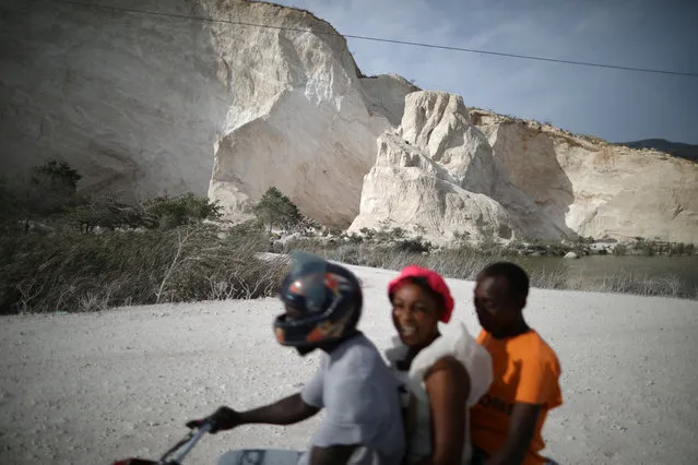 People ride a motorbike along a road next to a sand mine on the outskirts of Fond Parisien, March 21, 2018. (Photo by Andres Martinez Casares/Reuters)