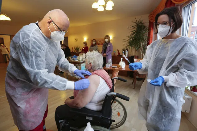 Doctor Bernhard Ellendt, left, injects the COVID-19 vaccine to a nursing home resident in Halberstadt, Germany, Saturday, December 26, 2020. The first shipments of coronavirus vaccines have arrived across the European Union as authorities prepared to begin administering the first shots to the most vulnerable people in a coordinated effort on Sunday. The vaccines developed by BioNTech and Pfizer arrived by truck in warehouses across the continent on Friday and early Saturday after being sent from a manufacturing center in Belgium before Christmas. (Photo by Matthias Bein/dpa via AP Photo)