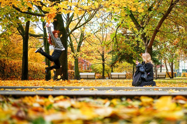 A woman throws fallen leaves and jumps while posing for a photo at the Bauman garden in Moscow, Russia, Tuesday, October 14, 2025. (Photo by Pavel Bednyakov/AP Photo)