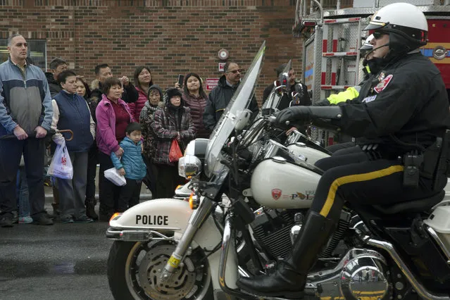 Onlookers stand to the side as motorcycle riding police officers lead the procession route during the funeral of New York Police Department Officer Wenjian Liu, Sunday, January 4, 2015. (Photo by John Minchillo/AP Photo)