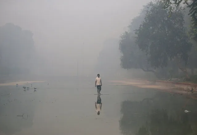 A man walks in a pond on a smoggy morning in New Delhi, India, October 31, 2016. (Photo by Cathal McNaughton/Reuters)