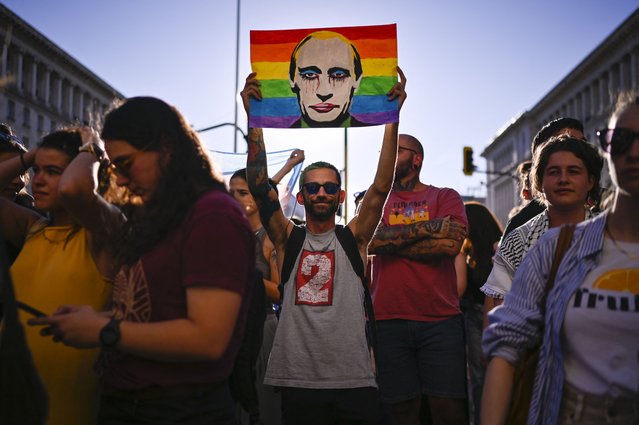 A protester holds a portrait of Russia's President Vladimir Putin against a Rainbow flag during a demonstration against a new law banning LGBTQ “propaganda” in schools in Bulgaria, in Sofia on August 07, 2024. Bulgaria's parliament passed changes to its education law on August 7, 2024 widening its scope to ban LGBTQ "propaganda" in schools in what rights groups slammed as "discriminatory". The amendment to the law, proposed by the country's pro-Russian Vazrazhdane party, passed by a large majority, with 159 votes in favour, 22 against and 12 abstentions. The law now bans the “propaganda, promotion or incitement in any way, directly or indirectly, in the education system of ideas and views related to non-traditional sexual orientation and/or gender identity other than the biological one”. (Photo by Nikolay Doychinov/AFP Photo)
