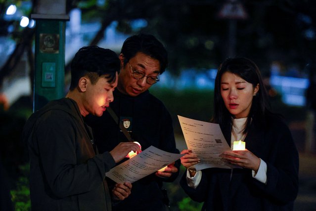 People hold prayer sheets, following the deadly fire at the Wang Fuk Court housing complex in Tai Po, Hong Kong, China on November 28, 2025. (Photo by Maxim Shemetov/Reuters)