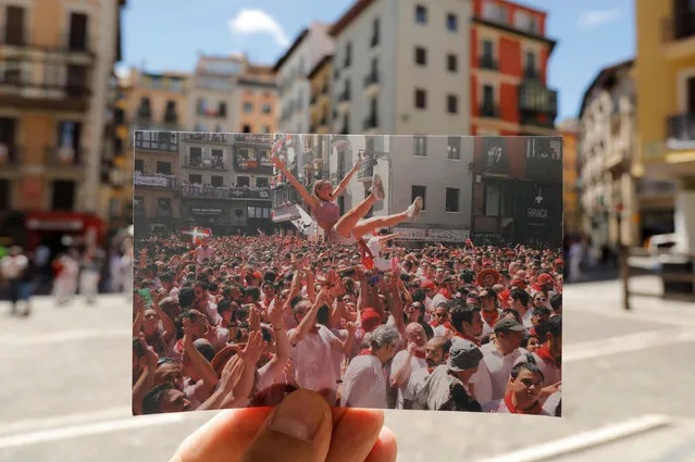 A Reuters photographer holds a picture of revellers celebrating during the opening of “chupinazo”, taken in July 2019, in front of the square where the firing of “chupinazo” took place, which opens the San Fermin festival that was cancelled due to the coronavirus disease (COVID-19) outbreak, should have taken place, in Pamplona, Spain on July 6, 2020. (Photo by Jon Nazca/Illustration/Reuters)