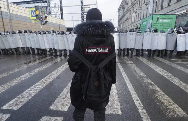 A man with a sign “Navalny” on his back stands in front of riot policemen blocking the way to protester during a protest against the jailing of opposition leader Alexei Navalny in St. Petersburg, Russia, Sunday, January 31, 2021. (Photo by Dmitri Lovetsky/AP Photo)