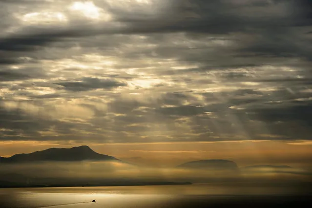 A boat cruises on the lake Geneva near Lausanne, Switzerland, 16 December 2015, as the sun breaks through the clouds. (Photo by Jean-Christophe Bott/EPA)