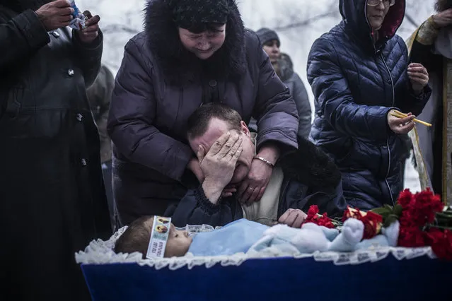 In this Tuesday, January 20, 2015 file photo, Vladimir Bovrichev, 30, cries next to the body of his son Artiam, 4, who was killed in an artillery strike, during his funeral in Kuivisevsky district on the outskirts of Donetsk, eastern Ukraine. (Photo by Manu Brabo/AP Photo)