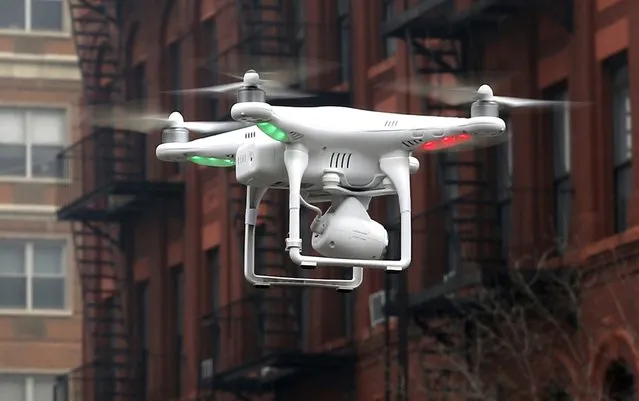 A camera drone operated by a civilian flies near the scene where two buildings were destroyed in an explosion in New York, in this file photo taken March 12, 2014. Some 73 percent of respondents to a Reuters/Ipsos online poll released on Thursday said they want regulations for the lightweight, remote-control planes that reportedly have been involved in an increasing number of close calls with aircraft and crowds. (Photo by Mike Segar/Reuters)