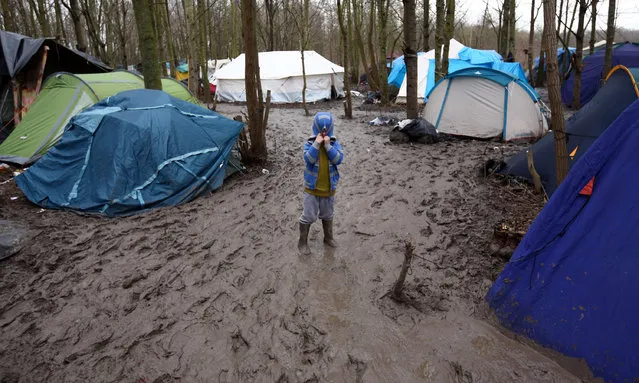 A boy hides his face in his hood as he negotiates thick mud in a new migrant camp on January 6, 2016 in Dunkirk, France. Thousands of migrants continue to live in makeshift camps in the port towns of Calais and Dunkirk in northern France, where they try and board vehicles heading for ferries or through the channel tunnel in an attempt to reach Britain. (Photo by Carl Court/Getty Images)
