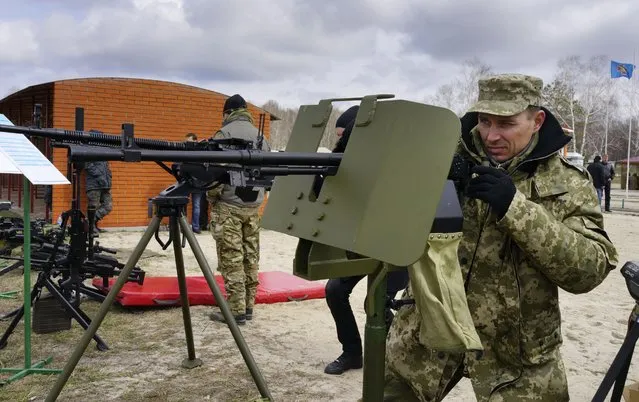 A serviceman inspects a machine gun during a presentation of new samples of Ukrainian-made weapons for the Ukrainian Army at a military base in Novi Petrivtsi outside Kiev, Ukraine, Saturday, April 4, 2015. (AP Photo/Efrem Lukatsky)