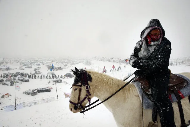 A woman stands on horseback as veterans join activists in a march to Backwater Bridge just outside the Oceti Sakowin camp during a snow fall as “water protectors” continue to demonstrate against plans to pass the Dakota Access pipeline adjacent to the Standing Rock Indian Reservation, near Cannon Ball, North Dakota, U.S., December 5, 2016. (Photo by Lucas Jackson/Reuters)
