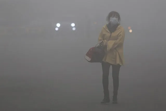 A woman wearing a face mask walks in heavy smog in Haerbin, northeast China's Heilongjiang province, on Oktober 23, 2013. Clouds of pollution blanketed Haerbin, cutting visibility to 10 metres (33 feet). (Photo by AFP Photo)
