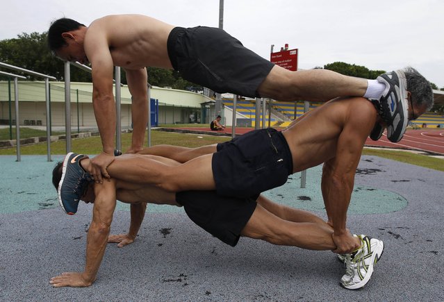 Ng Bee Kia (bottom to top), 70, Ngai Hin Kwok, 66, and Ng Siu Chi, 57, who form Team Strong Silvers, a team of senior citizens who train in calisthenics, perform stacked push-ups at a stadium in Singapore March 15, 2015. (Photo by Edgar Su/Reuters)
