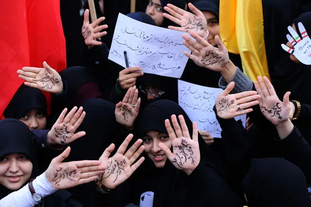 Iranian girls take part in a demonstration outside the former US embassy in the Iranian capital Tehran on November 4, 2018, marking the anniversary of its storming by student protesters that triggered a hostage crisis in 1979. Farsi writing on their palms praising the supreme leader Ayatollah Ali Khamenei. Thousands joined rallies in Tehran and other Iranian cities, carrying placards that mocked President Donald Trump, wiping their feet on fake dollar bills, and engaging in the usual ritual of burning the US flag. (Photo by Atta Kenare/AFP Photo)