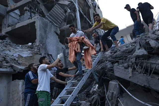 Palestinians rescue a young girl from the rubble of a destroyed residential building following an Israeli airstrike, Tuesday, October 10, 2023. The militant Hamas rulers of the Gaza Strip carried out an unprecedented attack on Israel Saturday, killing over 900 people and taking captives. Israel launched heavy retaliatory airstrikes on the enclave, killing hundreds of Palestinians. (Photo by Fatima Shbair/AP Photo)