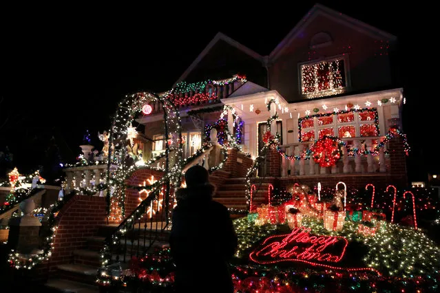 A man stands outside a decorated house at the Dyker Heights Christmas Lights in the Dyker Heights neighborhood of Brooklyn, New York City, U.S., December 23, 2016. (Photo by Andrew Kelly/Reuters)