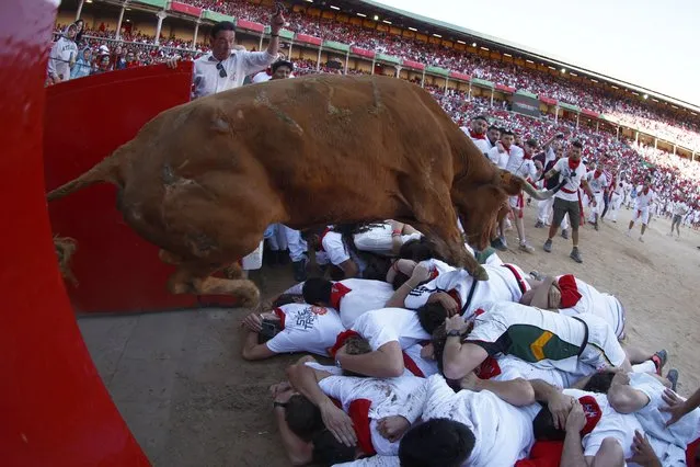 People take part in the traditional Running of the bulls during the San Fermin Festival in Pamplona, Navarra, Spain, 08 July 2022. Pamplona's Running of the Bulls, known locally as Sanfermines, resumed after a two-year hiatus due to the COVID-19 pandemic. The bull-running fiesta is held annually from 06 to 14 July in commemoration of the city's patron saint. Visitors from all over the world attend the festival. Many of them physically participate in the highlight event – the running of the bulls, or encierro – where they attempt to outrun the animals along a route through the narrow streets of Pamplona's old city. (Photo by Rodrigo Jimenez/EPA/EFE)