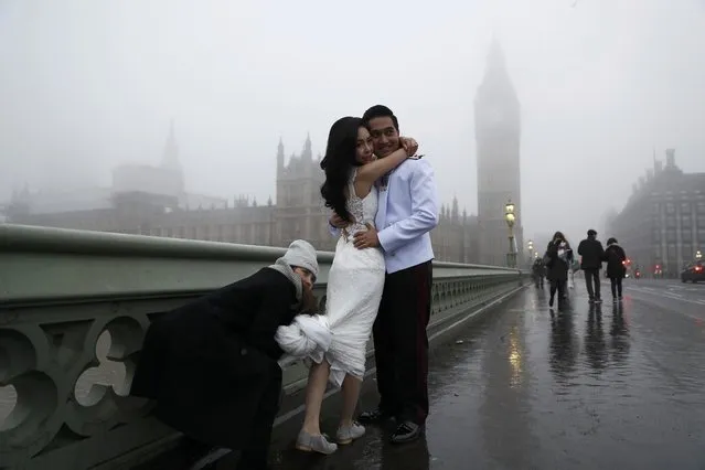 A couple from Thailand pose for a wedding photographer on Westminster Bridge during a foggy morning in central London, Britain December 30, 2016. (Photo by Stefan Wermuth/Reuters)