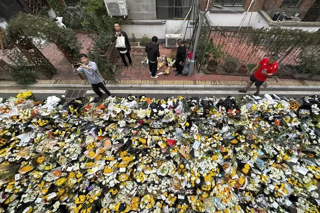Residents take pictures as they walk by flowers laid outside a residential building where the late Chinese Premier Li Keqiang spent his childhood in Hefei city, in central China's Anhui province, Saturday, October 28, 2023. The sudden death of China's former second-ranking leader, Li Keqiang, has shocked many people in the country, with tributes offered up to the ex-official who promised market-oriented reforms but was politically sidelined. (Photo by Chinatopix via AP Photo)