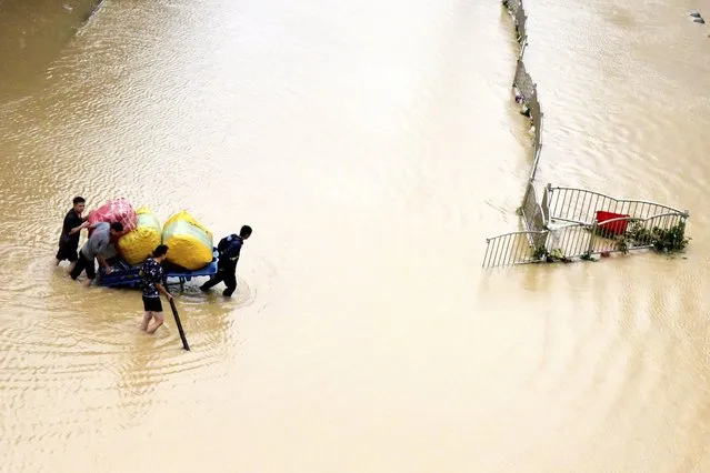 In this photo released by Xinhua News Agency, residents move their belongings across a flooded street in Zhengzhou in central China's Henan province on Wednesday, July 21, 2021. (Photo by Zhu Xiang/Xinhua via AP Photo)