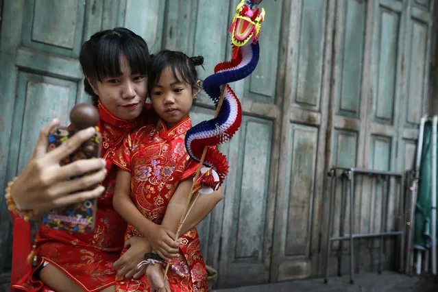 A woman and her daughter dressed in traditional chinese clothes take a picture while celebrating Chinese New Year at Chinatown in Bangkok, Thailand February 8, 2016. (Photo by Jorge Silva/Reuters)