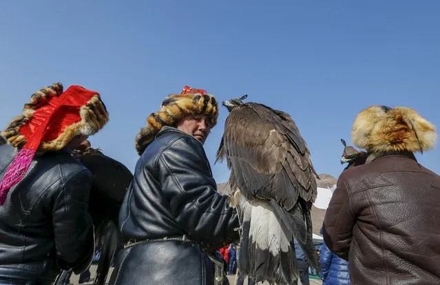A hunter holding his tamed golden eagle looks back at a parade during the traditional hunting contest outside the village of Nura, east from Almaty, Kazakhstan, February 13, 2016. (Photo by Shamil Zhumatov/Reuters)
