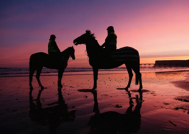 Two riders pause to watch the sunrise as they exercise their horses at first light as a dramatic sky starts the day over the beach on February 16, 2016 in Saltburn-by-the-Sea, England. Temperatures remain low across parts of the country with many areas affected by snow and freezing temperatures. (Photo by Ian Forsyth/Getty Images)