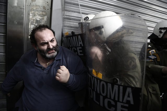 A hospital worker resists against riot police during a protest against planned pension reforms by the Greek government outside the entrance of the Finance Ministry during a protest against planned pension reforms by the Greek government, in Athens, Greece, 18 February 2016. (Photo by Yannis Kolesidis/EPA)